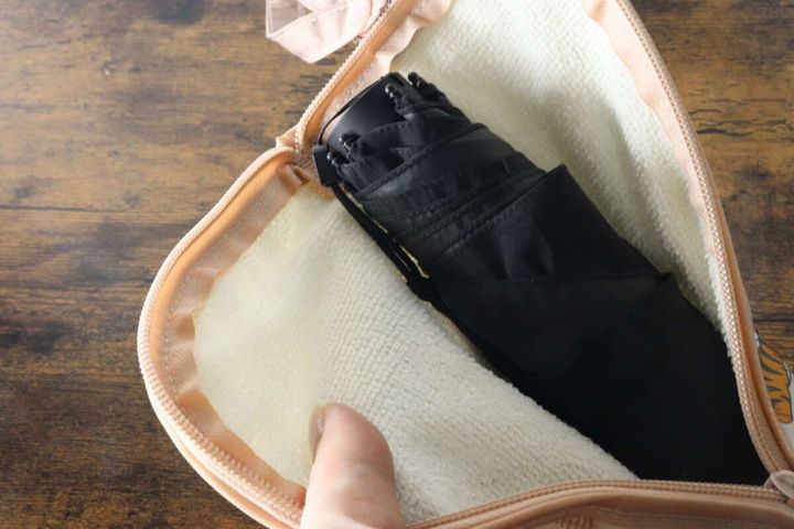 傘収納袋に黒い折りたたみ傘を入れている様子