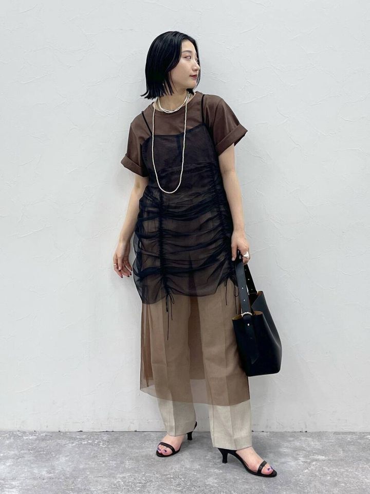 茶色Tシャツと黒チュールワンピを重ね着した女性の全身コーデ