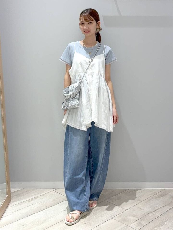 水色Tシャツと白チュニックにワイドデニムを合わせた女性