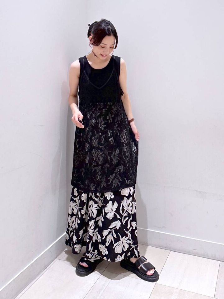 黒いレースキャミチュニックと花柄スカートを合わせた女性