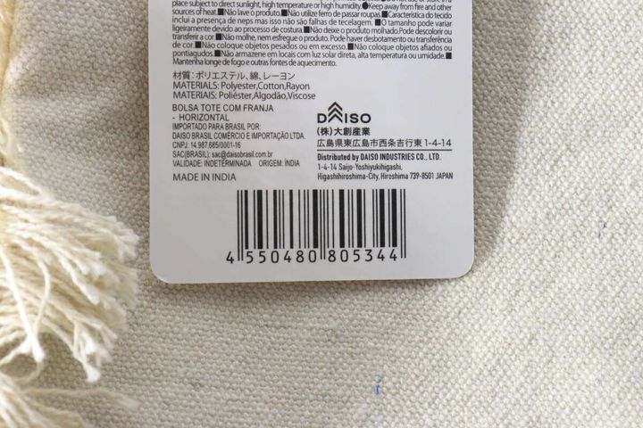 白いフリンジトートバッグに付いている商品タグの裏面、バーコードと商品情報が写っているクローズアップ