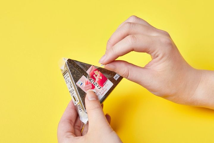 両手がおにぎり型消しゴムのパッケージをピリピリと開封している