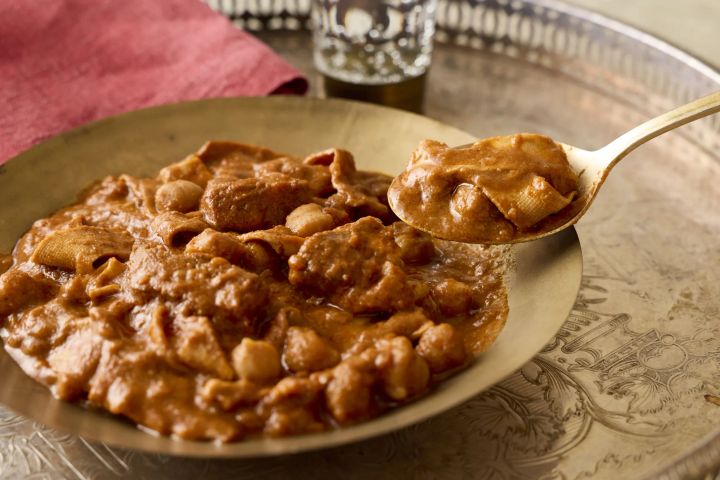 金色の皿に盛られたマサラカレーと金色のスプーンですくう豆腐干