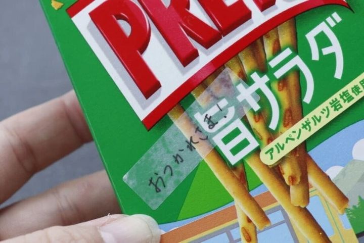 お菓子の箱に半透明シールを貼りメッセージを書いている。