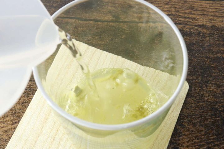 グラスに入った玄米茶の粉末に、透明な容器から水を注いでいる様子
