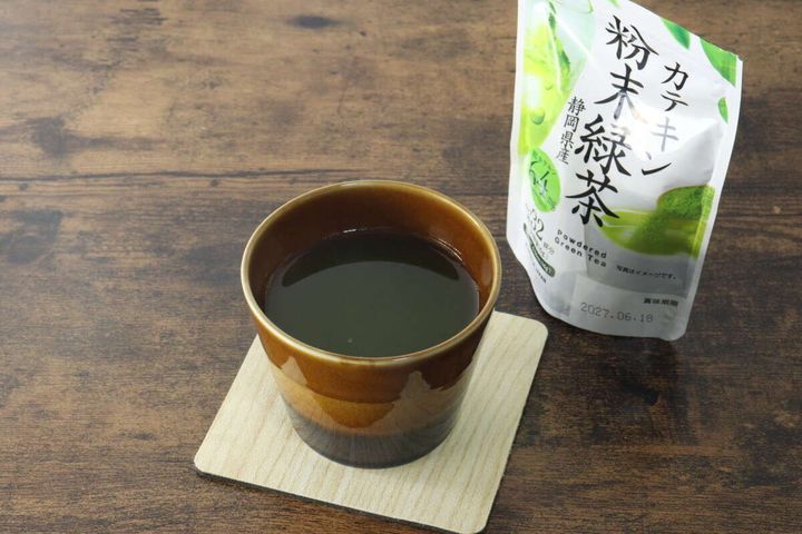 茶碗に入った濃い緑色の緑茶と、奥に「カテキン粉末緑茶」パッケージ