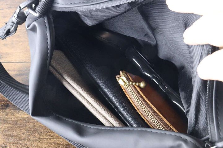 黒いショルダーポーチに長財布やスマホなどが収納されている