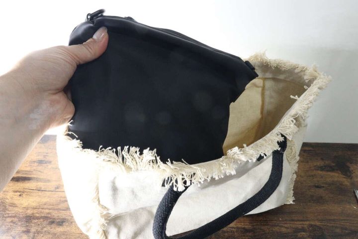 黒いショルダーポーチをトートバッグに入れている手元
