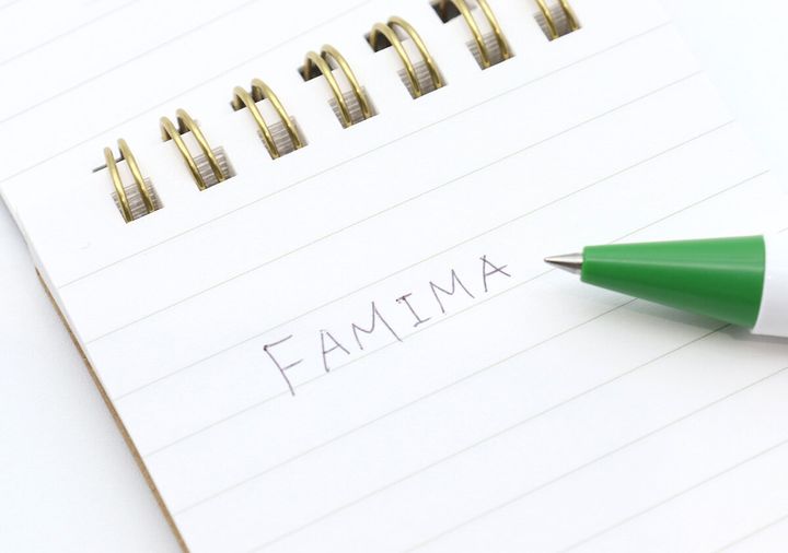 FAMIMAボールペンで白いノートに「FAMIMA」と書いているクローズアップ写真