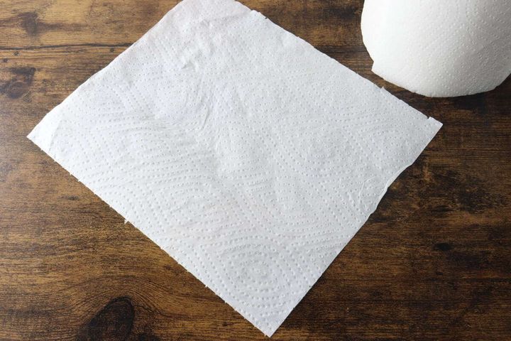 木目調のテーブルに広げられたエンボス加工の白いキッチンペーパー1枚