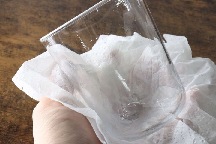 キッチンペーパーでグラスに残った水滴を拭き取っている手元