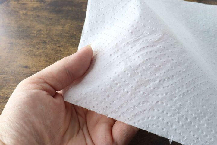 女性が指でキッチンペーパーの薄さを確認している様子
