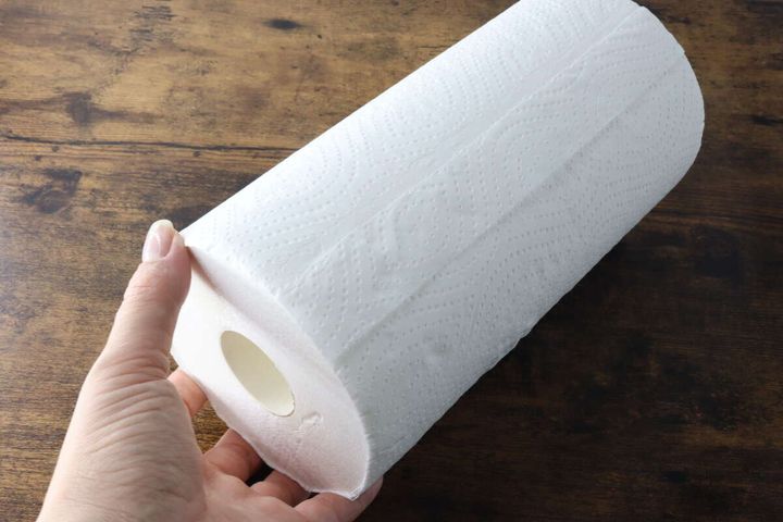 女性の手がロール状のダイソー単層キッチンペーパーを持っている
