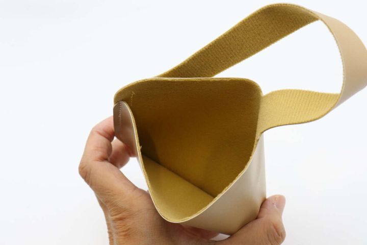 ベージュ色のポーチの内部を手で広げて見せている