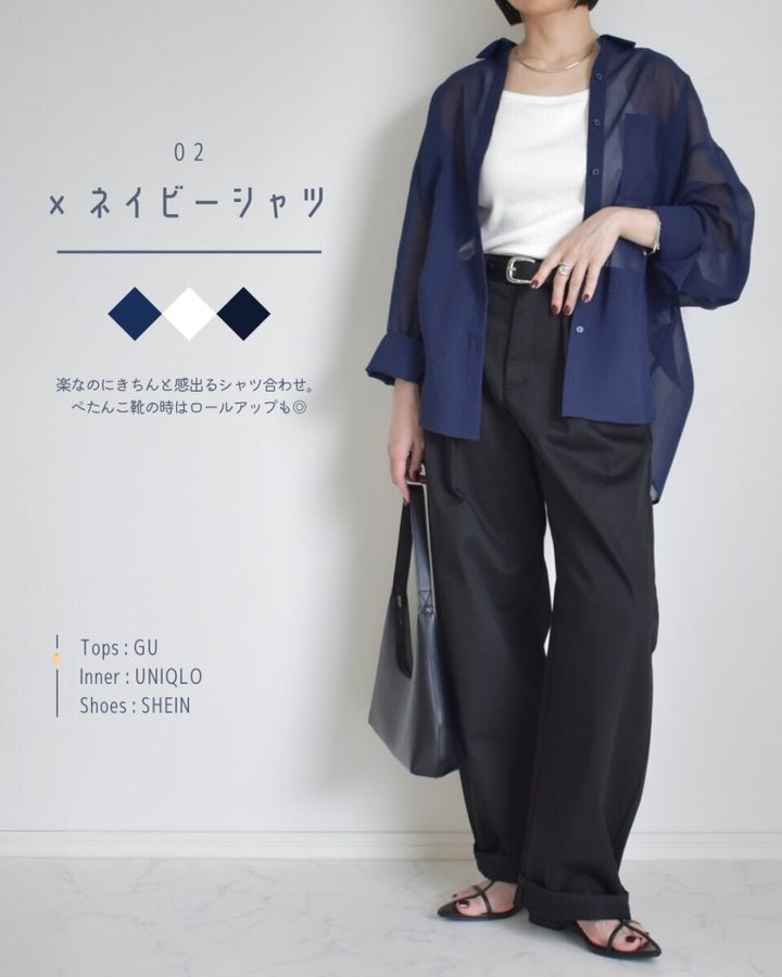 黒いバレルパンツにネイビーのシアーシャツと白いインナーを合わせた女性の全身。黒いサンダルを履いている