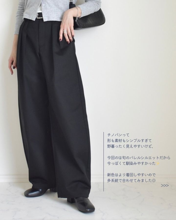 黒いバレルパンツを着用した女性の全身。グレーのカーディガンと黒いバッグを合わせている