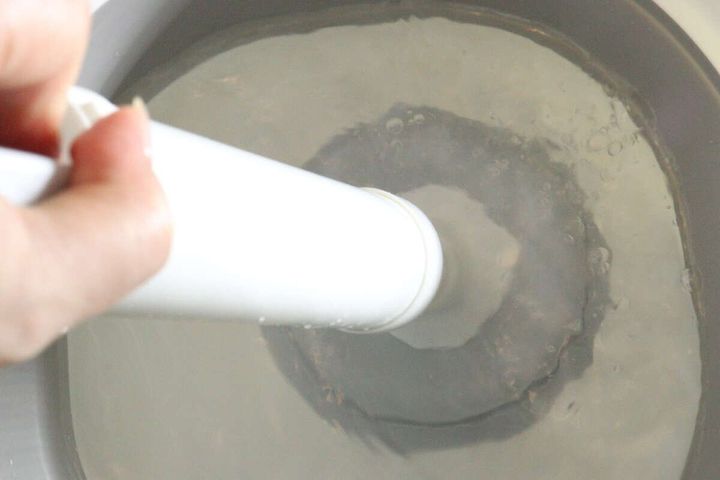 パイプクリーナーを桶の水中で押し引きして吸引力を試している