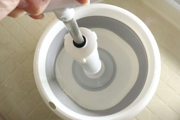 パイプクリーナーを水が入った白い桶に差し込んでいる