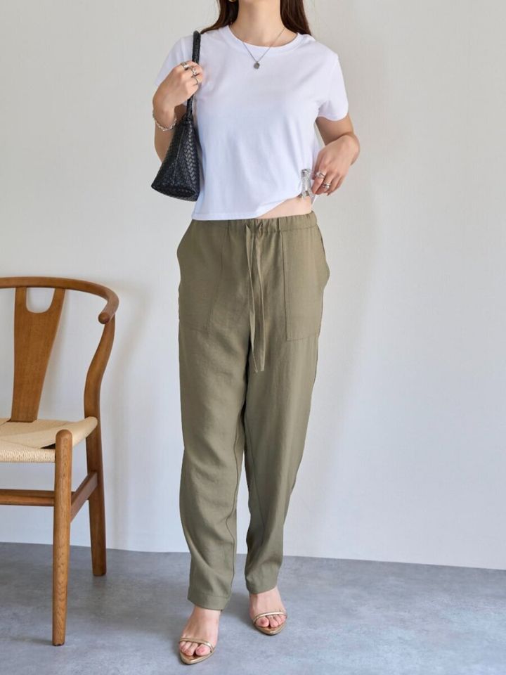 白Tにカーキのテーパードパンツを合わせ、黒バッグを持つ女性