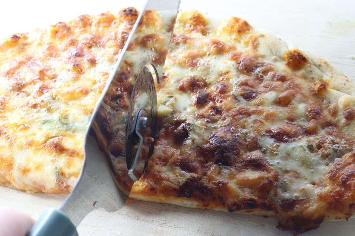 焼きたてのピザを一体型ピザサーバーのローラーカッターでカットしている様子