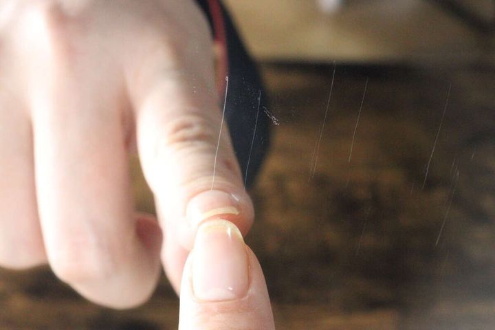 女性の指がステッカーミラー表面の細い傷を指し示しているクローズアップ