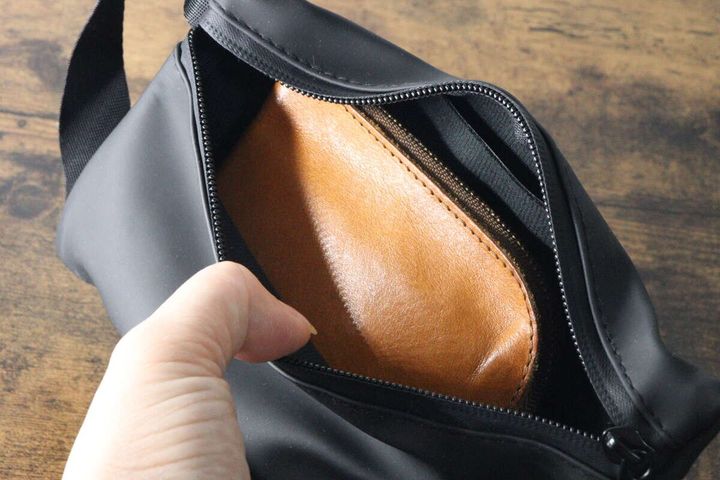 ポーチに茶色い財布を入れる手元