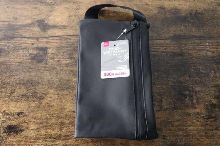 木目テーブルに置かれた黒い取っ手付ポーチ