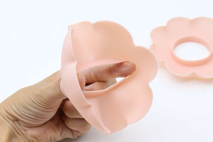 指でピンクの花形洗顔リストバンドの柔らかさを確認