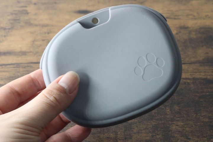 女性の手のひらに乗せられた、肉球マーク付きのグレーのおやつポーチ