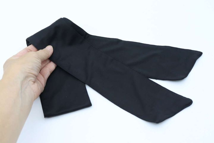 女性の手が黒い「2WAY ポケット付スカーフ」を広げている