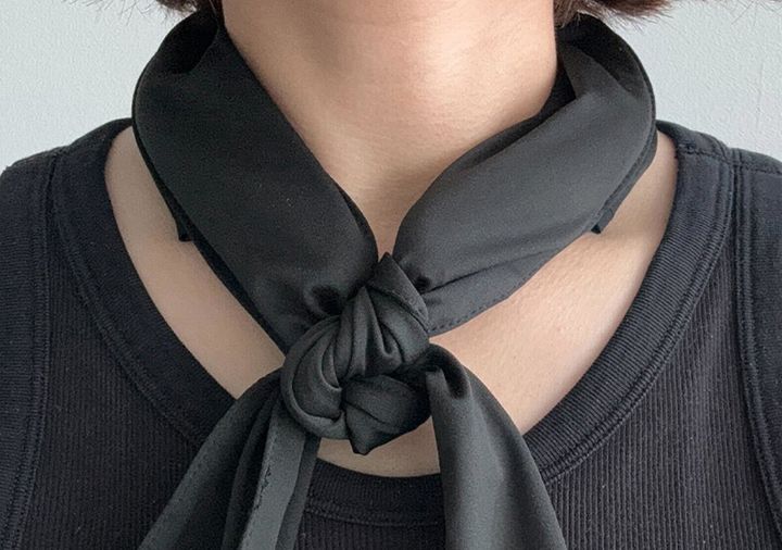 黒いスカーフを首に巻いて結んでいる女性の胸元