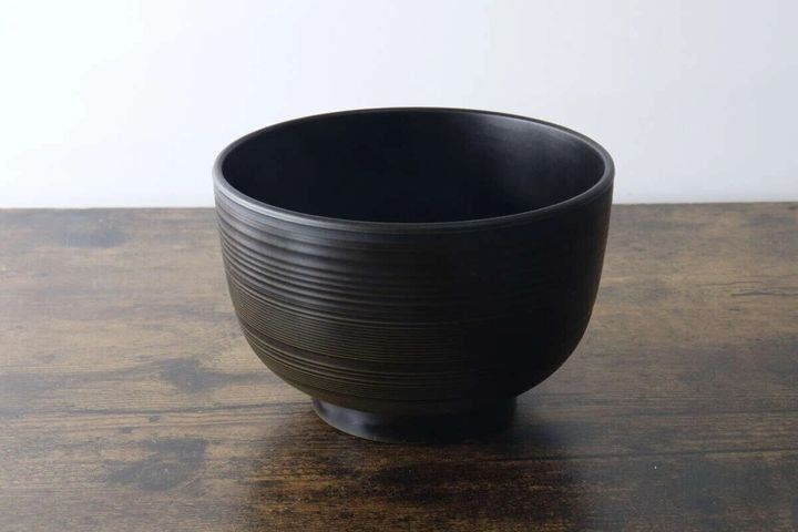 こげ茶色の会津塗の汁椀が木製のテーブルに置かれている