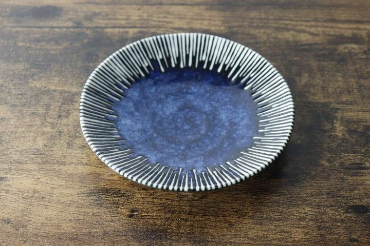 紺色の釉薬と放射状の模様が特徴的なたれ皿が木製のテーブルに置かれている俯瞰