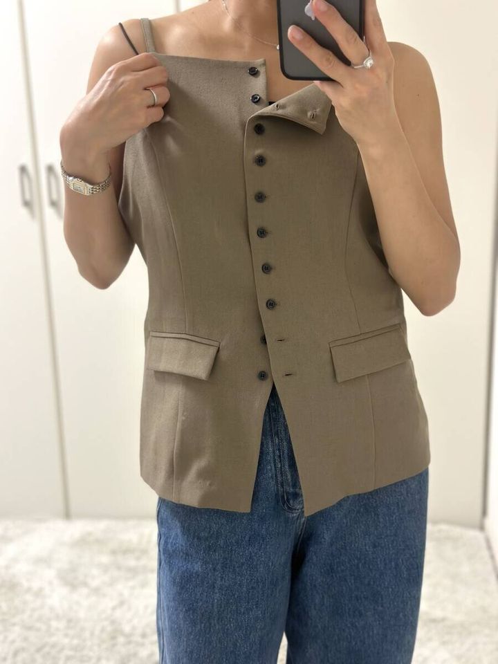 ベージュのツイードキャミトップスを試着する女性