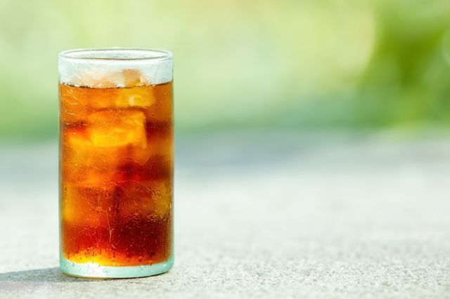 ガラスコップに入った黒烏龍茶 イメージ 背景に緑