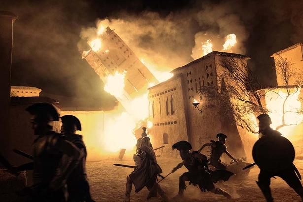 ギリシャ軍の攻撃により、炎上するトロイアの城郭都市(『オデュッセイア』) [c] 2026 UNIVERSAL STUDIOS