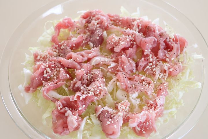 耐熱皿に広げたキャベツと豚こま切れ肉