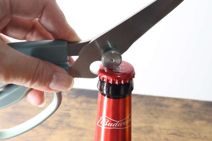立つキッチンハサミの栓抜き機能で瓶の蓋を開けている手元