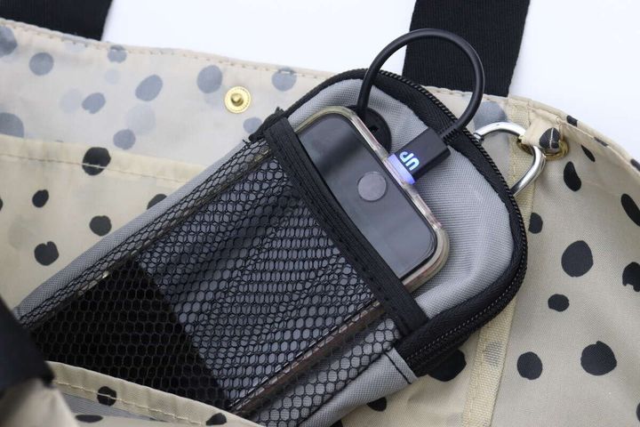 ドット柄のバッグにカラビナで吊り下げられたモバイルバッテリーケース