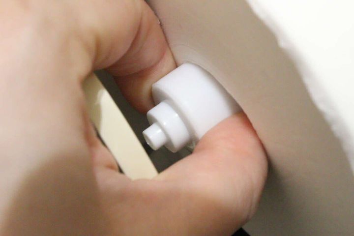 女性の手が新しい替え芯ホルダーをトイレットペーパーホルダーに差し込んでいる