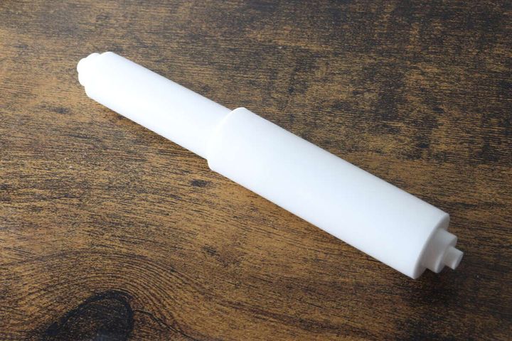 木目調のテーブルに置かれた白いトイレットペーパー替え芯ホルダー