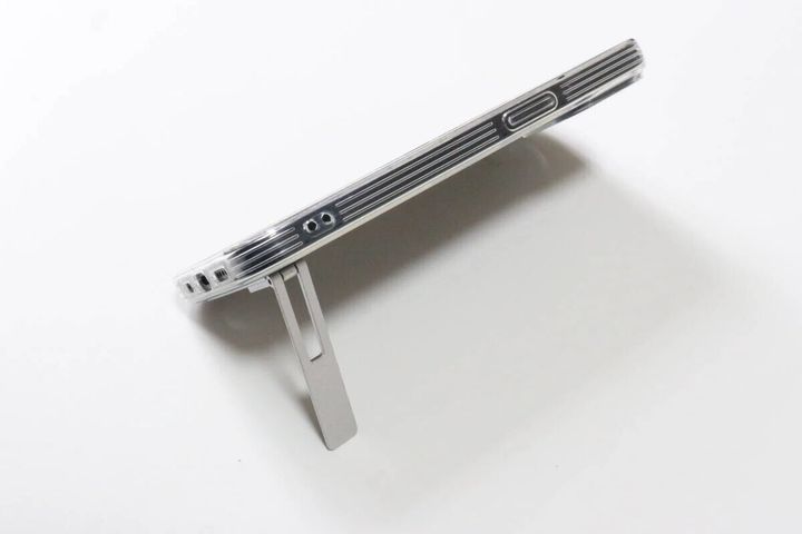 透明なスマホケースの背面に貼り付けられたスタンドを開いて立てた状態