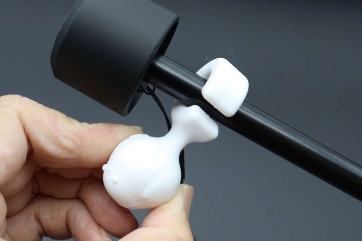 手が白いシマエナガ型ストッパーを黒い折りたたみ傘の中棒に取り付けている