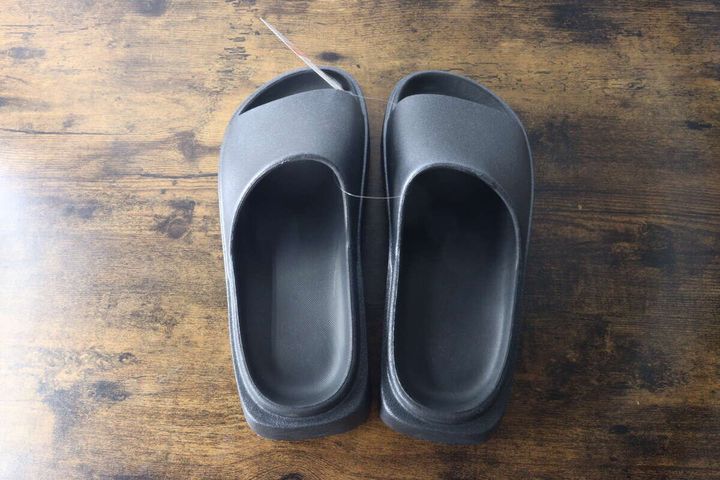 木目のテーブルに置かれた黒いEVAサンダル2足の俯瞰写真