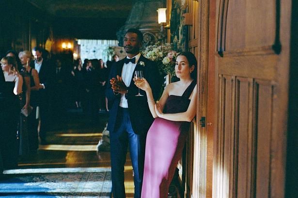 チャーリーの親友マイク(ママドゥ・アティエ)とレイチェル(アラナ・ハイム)の夫婦が付添人に [c] 2026 Dramatic Movie Rights LLC. All Rights Reserved.