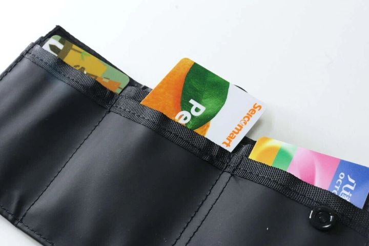 黒い三つ折り財布を開きカードポケットにカードが並んで収納されている