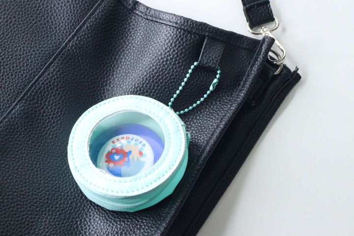 黒いバッグに水色の缶バッジケースが取り付けられている