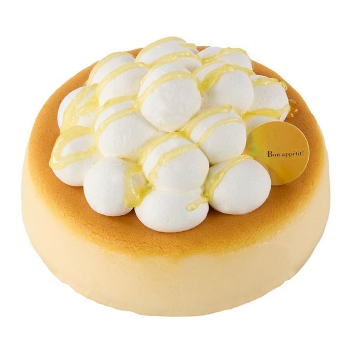 丸いスフレチーズケーキにホイップクリームとレモンソースがかけられている