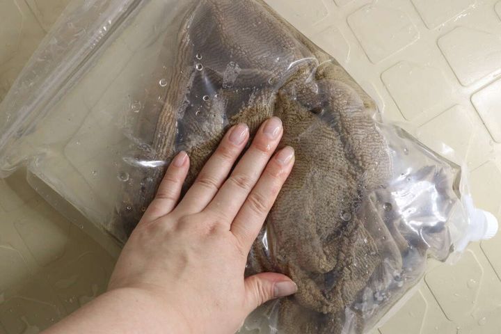 ウォッシュバッグに入ったタオルを上から手で揉み洗い