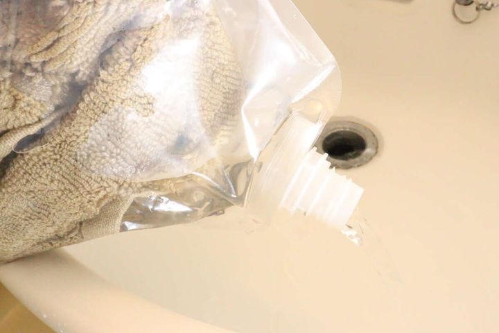 ウォッシュバッグのキャップから洗面台に水を排出している